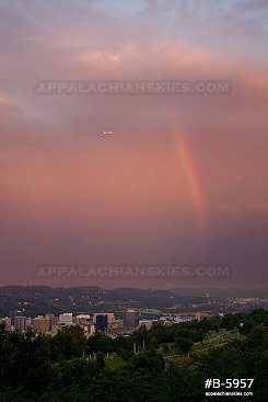A jet plane takes off amid a rare morning rainbow in the western sky over Charleston