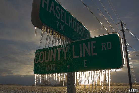 Sunlit thick icicles on street signs after an ice storm