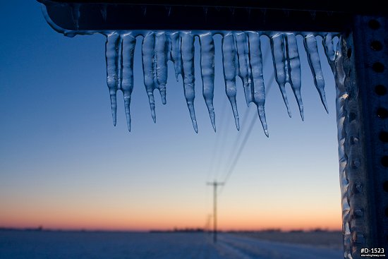 Icicles on a prairie road sign with sunrise glow after an ice storm